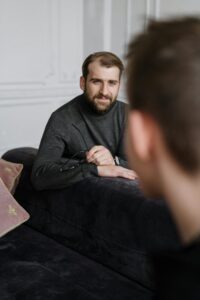 A therapist listens attentively to a client during a counseling session in an office setting.